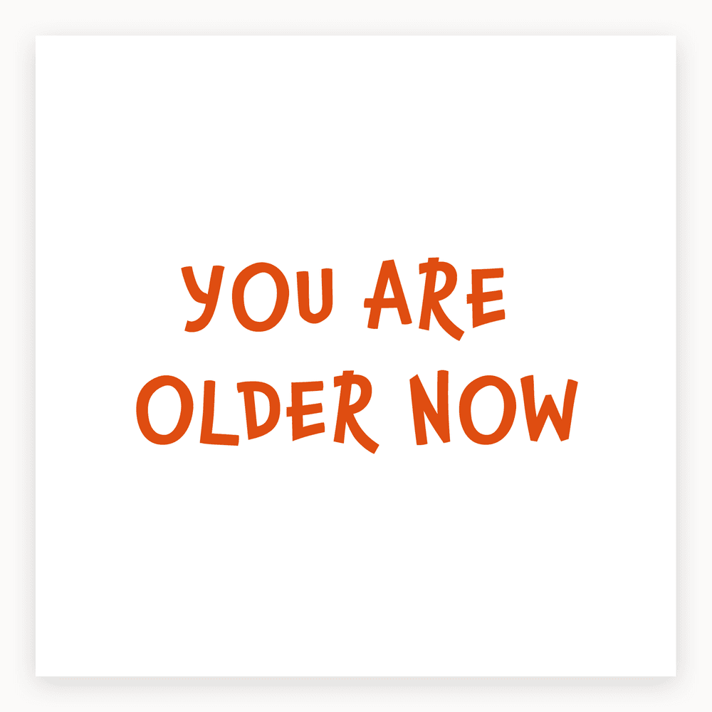 The card lying flat. Birthday card with 'YOU ARE OLDER NOW' in bold orange letters on a white background.